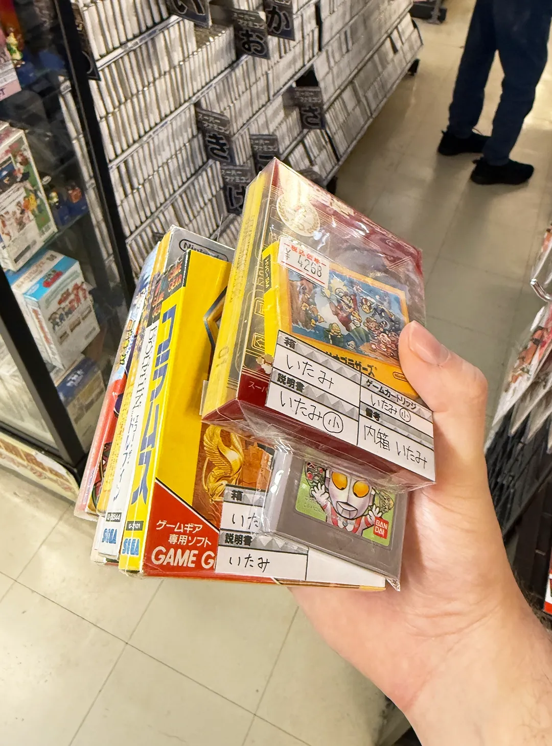 Brandon holding a stack of games for various consoles inside Super Potato