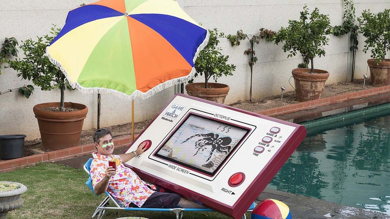 Tom Tilley sitting by a pool with a giant game and watch