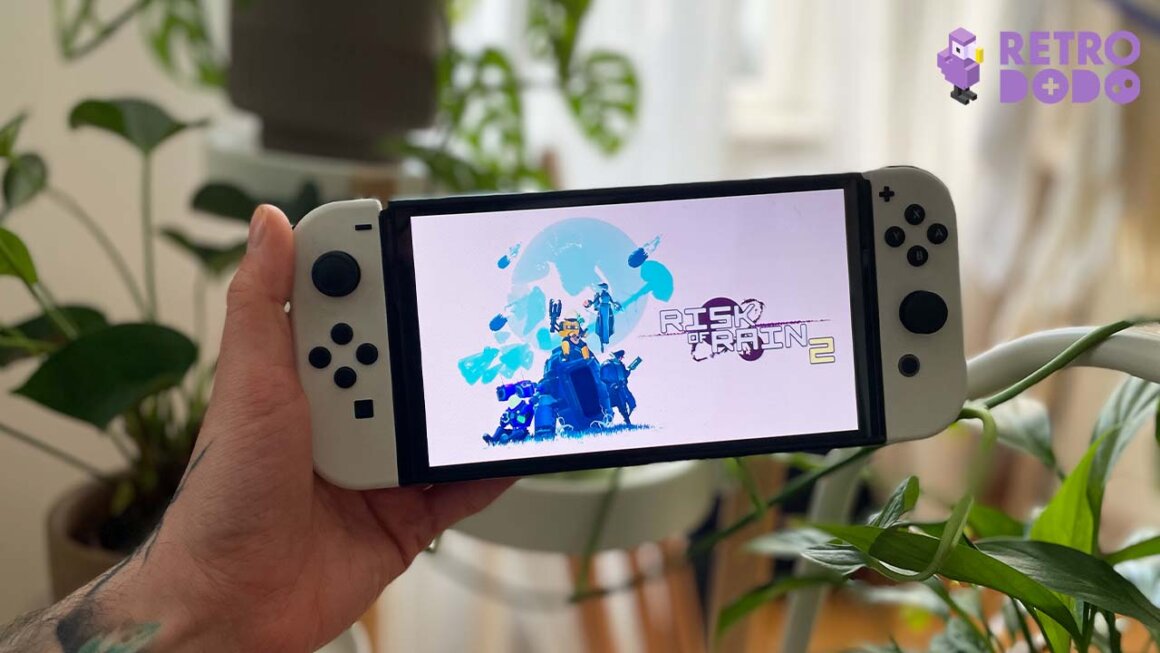 Seb's hand with a Nintendo switch. The screen shows Risk of Rain 2 game logo