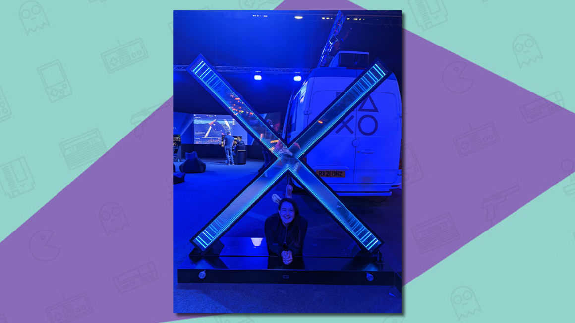 Rosie Caddick lying under a giant Cross symbol at a PlayStation event.