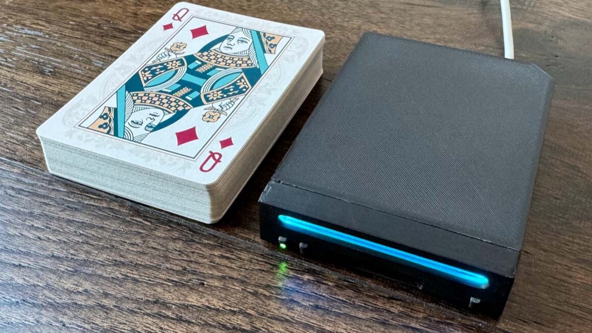 The short stack Nintendo Wii MIni console sitting next to a pack of cards.